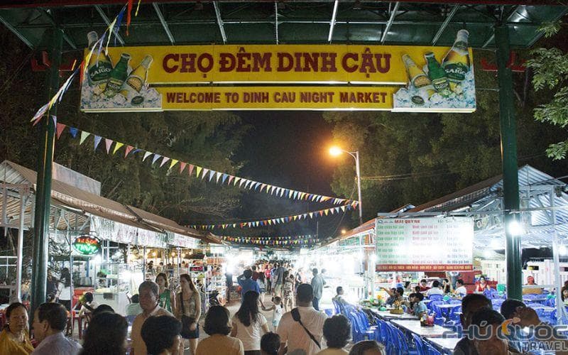 Dinh Cau Night Market, welcoming visitors to an area lined with stalls and rows of blue plastic seating